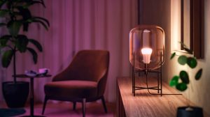Eine smarte Philips Hue Lampe in einer gläsernen Leuchte taucht das Wohnzimmer in ein warmes Glühen.