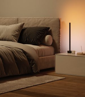 De zijkant van een bed baadt in warmwitte tinten licht van een Signe tafellamp.