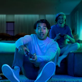 Ein Paar vertieft sich in ein Videospiel bei smartem Licht in Blautönen.