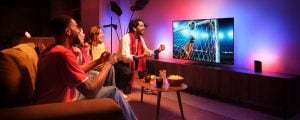 A group of friends celebrate a goal seen on a TV football match with the Hue Sports Live feature making lights react to the moment in tones of pink and blue.