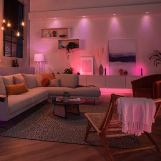 Una sala de estar iluminada con suaves tonos primaverales de rosa, morado y luz blanca.