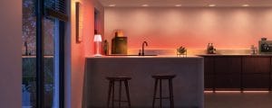 Un mostrador de cocina iluminado con tonos cálidos anaranjados y blancos de luz inteligente.