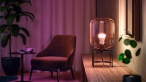 A Philips Hue smart bulb inside a glass lamp casts a warm glow around a living room space.