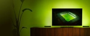 Un'immagine di uno stadio di calcio proiettata sulla TV, circondato da toni verdi di luce, che promuove l'offerta di illuminazione Hue Sports Live.