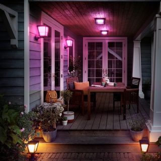 Un portico con un tavolo da giardino e le sedie; le luci smart sono accese.