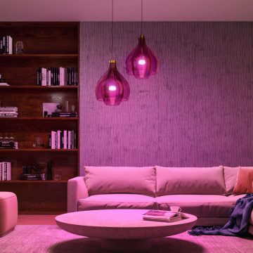 Philips Hue 스마트 전구가 장착된 두 개의 펜던트 조명으로 핑크색 스마트 조명이 켜진 거실 