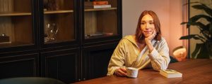 En person kopplar av vid matbordet i ett ljust, inbjudande vardagsrum upplyst av varm Philips Hue smart ljus.