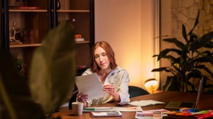 A woman holding documents in a workspace with soft, relaxing lighting in the background.