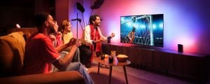 A group of friends celebrate a goal seen on a TV soccer match with the Hue Sports Live feature making lights react to the moments in tones of Pink and Blue.