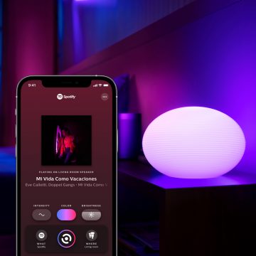 Inteligentní lampa na odkládacím stolku s mobilním zařízením zobrazujícím kartu Synchronizace v aplikaci Hue