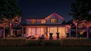 Die Fassade und der Garten eines Hauses sind mit Festavia LED-Eiszapfenlichterketten, Vorhanglichterketten, Netzlichterketten und Kugellichterketten dekoriert, die in sanften Farbverläufen in Rosa, Lila und Weiß erstrahlen. 