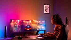 Eine Person spielt am Schreibtisch mit bunter, smarter Beleuchtung, die sich mit dem PC synchronisiert und das Entertainment-Erlebnis verstärkt.