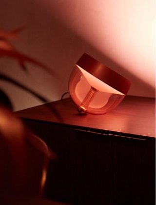 Eine Philips Hue Iris Tischleuchte leuchtet in einem warmen Weißton. 