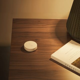 Ein weißer Philips Hue Smart Button auf einem Tisch neben einem Laptop.