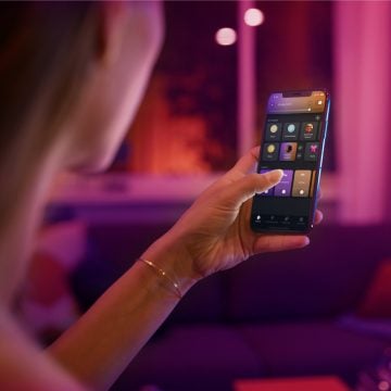 Hand hält ein mobiles Gerät, auf dem die Hue App zu sehen ist