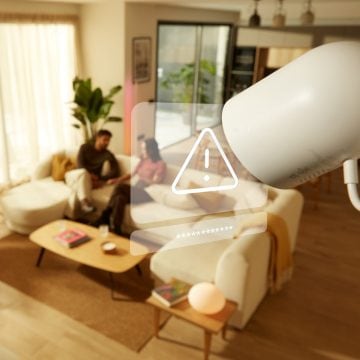 Eine 2K-Kamera nimmt zwei Personen auf, die auf einem Sofa im Wohnzimmer sitzen