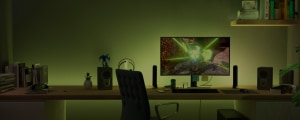 Gaming room desk with LED gaming room lights placed beside monitor, casting green light onto wall and workspace, monitor displaying game. 