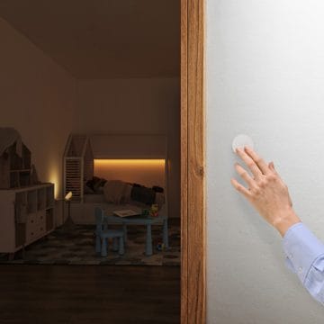 A woman's hand pressing the Hue smart button (latest model) to control the lights in a child's room