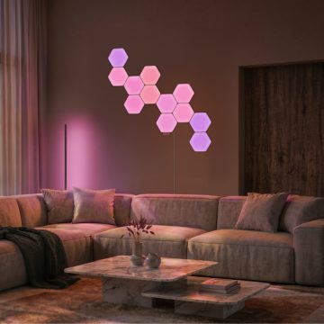 Nanoleaf hexagon modular wall light starter set integrated with a Philips Hue Signe gradient floor lamp lighting a contemporary living room in pink and purple tones of smart light.