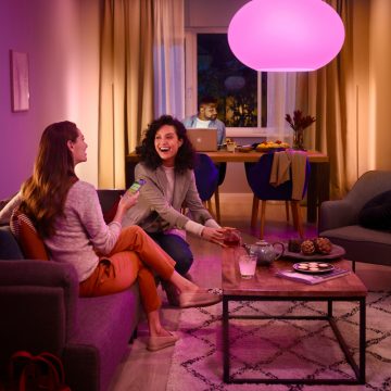Two friends on a sofa under the pink glow of Philips Hue smart light.