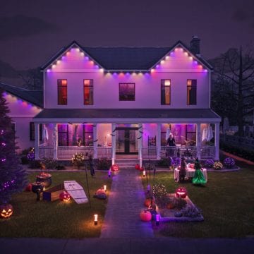 The exterior of a home illuminated with Festavia permanent outdoor lights glowing in multi-colors with a Halloween theme. 