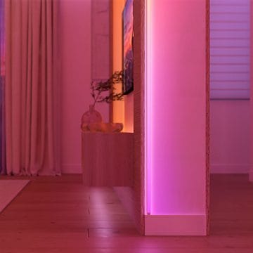 A split screen photo of a kitchen with one half showing the space lit with a wall washing effect in white light and the other half showing the space lit in pink and blue light.