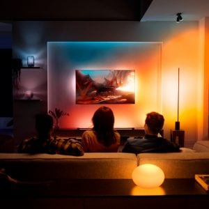 A group of people watching TV in a living room with lights that sync with TV for an immersive entertainment experience.