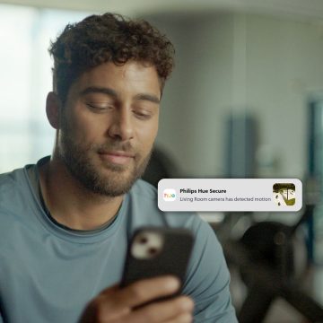 A man receives a motion detection notification on his smartphone via the Hue app. 