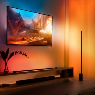A Philips Hue Play table and floor lamp positioned next to a TV creating surround lighting effect in purple, pink and yellow gradients of light.