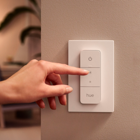 Hand pushing the button on a Philips Hue dimmer switch