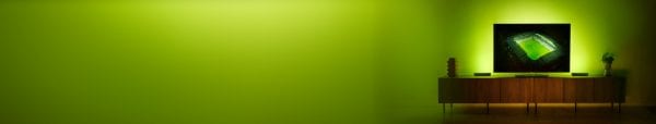 An image of a football stadium on a TV surrounded by green tones of light promoting Hue Sports Live lighting sale.