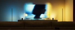 A TV in a modern living room, illuminated by Hue Play wall washer and Play lamps, which sync with the screen content to create an immersive and dynamic entertainment experience.