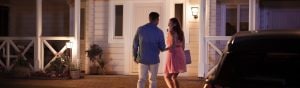 Two people approach a house entrance at night, illuminated by outdoor wall lights triggered by motion sensor lighting