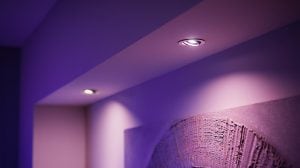 mr16 vs gu10 recessed smart bulbs installed in a ceiling, emitting colored light onto a wall and textured artwork below.