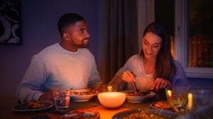 A couple sharing a meal at a dining table illuminated by a warm LED smart light centerpiece, showcasing smart LED gifting lighting ideas in a cozy indoor setting.