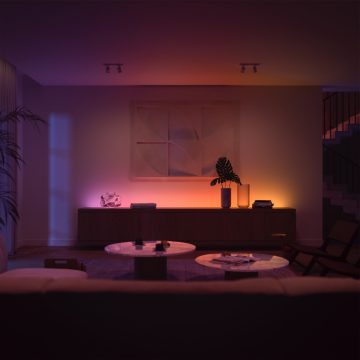 Modern living room with soft ambient glow in pink, orange, and blue tones, highlighting a sideboard and abstract wall art.