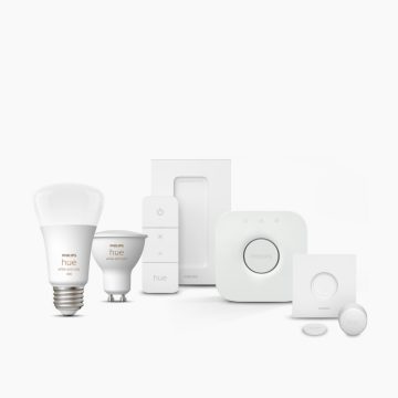 A collection of smart lighting products and accessories in white, including light bulbs, switches, a hub, and sensors, on a plain background.