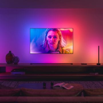Colorful smart lighting illuminates a living room as a television displays vibrant hues, enhancing the home entertainment setting.