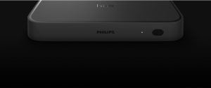 Black rectangular sync box with matte finish, front-facing button, indicator light, and visible ""PHILIPS"" and ""hue"" text.