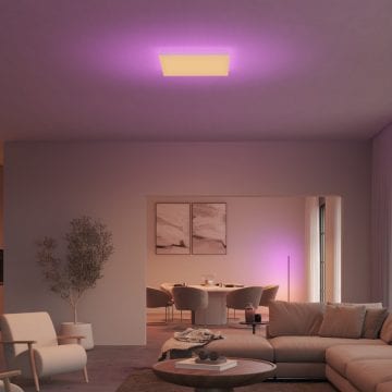 Rectangular ceiling light fixture emitting purple and white light, mounted above a living area with a sofa and armchair.