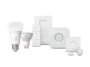 A collection of smart lighting products and accessories in white, including bulbs, sensors, a remote, and a central hub.