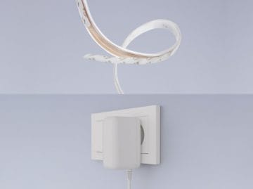 Two images showing a flexible lightstrip and its power adapter plugged into a wall outlet against a plain background.