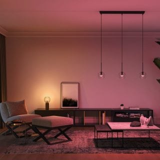 Modern living room with soft ambient glow from pendant and table lighting, highlighting neutral furniture and minimalist decor.