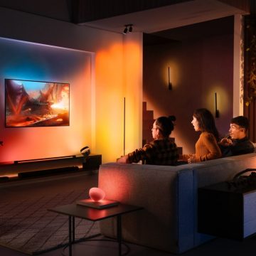 A group of people watching TV in a living room, surrounded by colorful smart lighting that matches the screen content.