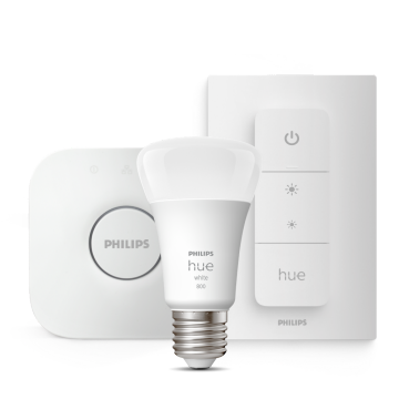 A white smart bulb, a wireless dimmer switch, and a square smart bridge are displayed against a plain background.