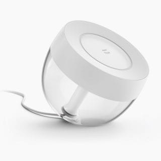 White compact round table lamp with a matte finish, transparent lower half, and visible power cord attached to the base.