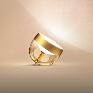 Limited edition Iris smart table lamp with a gold finish, rounded shape, transparent base, and compact design.