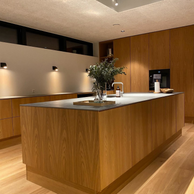 Wall-mounted smart lights illuminate a modern kitchen with wood cabinetry and a central island, highlighting workspace surfaces.