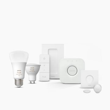 A collection of white smart lighting products and accessories, including bulbs, switches, and sensors, displayed on a plain background.