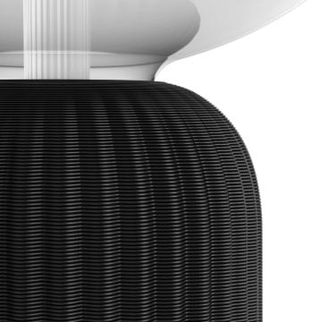 Close-up of a table lamp base made from ribbed black recycled material, showing textured surface and curved design features.
